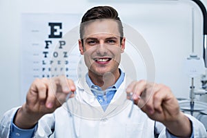 Smiling optometrist holding spectacles