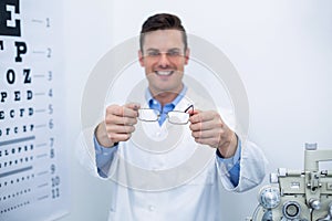 Smiling optometrist holding spectacles