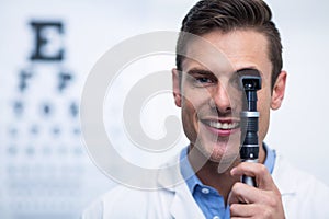 Smiling optometrist looking through ophthalmoscope