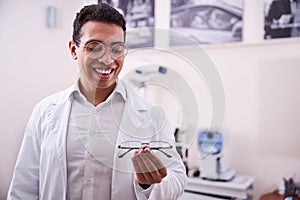 Smiling optometrist looking at prescription eyewear in his hand