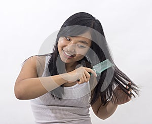 Smiling oriental girl brushing her hair