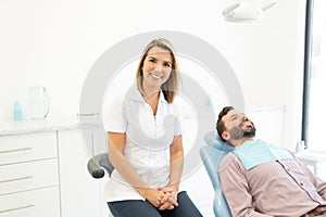 Smiling Orthodontist By Patient On Chair