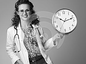 Smiling paediatrician doctor showing clock on