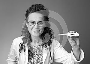 Smiling paediatrician doctor showing thermometer on photo