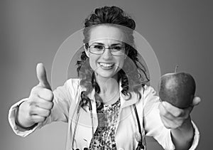 Paediatrician doctor giving an apple and showing thumbs up
