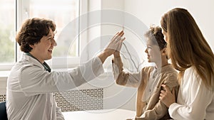 Smiling paediatrician greeting kid patient at checkup in clinic