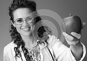 Smiling paediatrician woman giving an apple on