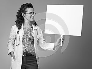 Smiling paediatrician woman looking at placard on