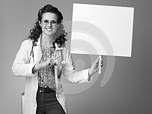 Smiling paediatrician woman pointing at placard on