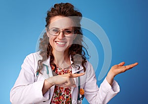 Smiling paediatrician woman pointing on something on empty palm