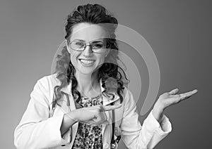 Smiling paediatrician woman pointing on something on empty palm