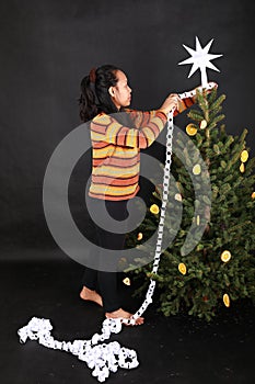 Smiling Papuan girl putting white paper chain on Christmas tree