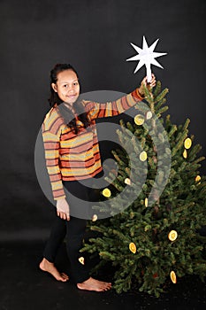 Smiling Papuan girl putting white star on top of Christmas tree