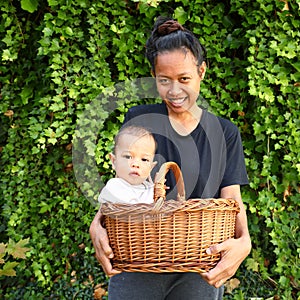 Smiling Papuan mom with baby in wicked basket