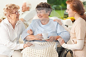 Smiling paralyzed senior woman with friend and nurse