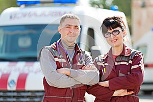 Smiling paramedics on ambulance car background