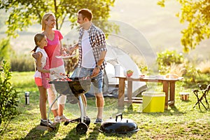 Smiling parent grilling meat with daughter