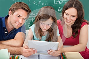 Smiling parents assisting daughter in using digital tablet