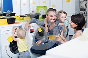 Smiling parents with kids shopping modern washer