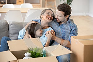 Smiling parents relax with daughter on home couch