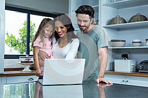 Smiling parents using laptop with daughter