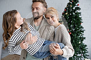 Smiling parents in warm cardigans holding