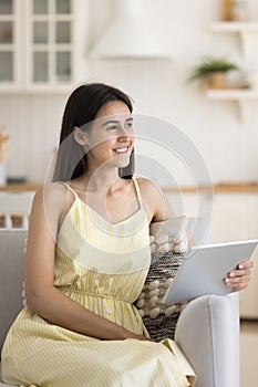 Smiling peaceful woman enjoy pastime at home using digital tablet