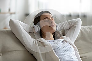 Smiling peaceful woman listening to favorite audio music in earphones.