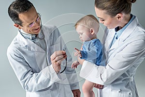 smiling pediatricians checking breath of adorable