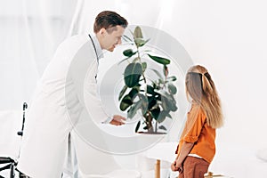 Pediatrist and child looking at green plant in clinic photo