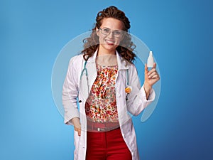Smiling pediatrist woman showing nasal drops on blue photo