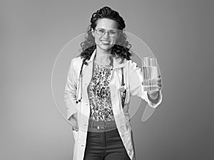 Smiling pediatrist woman giving glass of water on photo