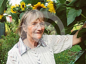 Smiling pensioner in her garden with sunflower