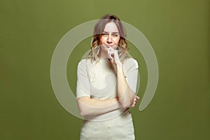 Smiling pensive beautiful 30s woman look at camera touching chin thinking posing on green studio background