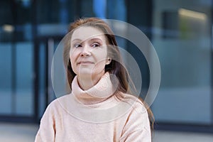 Smiling pensive middle aged woman. elderly businesswoman near business center. lecturer, teacher at university, adult lady