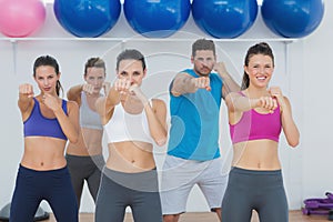 Smiling people doing power fitness exercise at yoga class