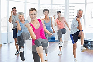 Smiling people doing power fitness exercise at yoga class