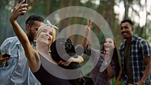 Smiling people having fun on bbq party outside. Man jokingly biting dog outdoors