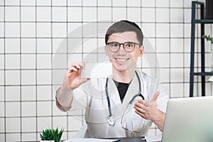 Smiling pharmacist holding a box of pills in the pharmacy