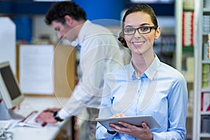 Smiling pharmacist holding digital tablet in pharmacy