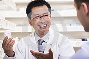 Smiling pharmacist showing prescription medication to a customer