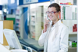 Smiling pharmacist talking on phone in pharmacy