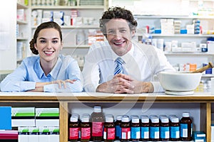 Smiling pharmacists leaning at counter in pharmacy