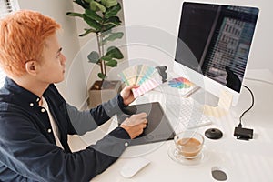 Smiling photo editor working on computer at desk with camera and
