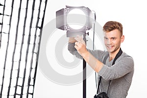 Smiling photographer is busy fixing the spotlight