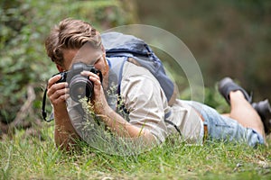 smiling photographer laying on grass with camera and flash