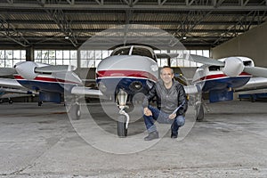 Smiling Pilot in front of Modern Private Airplane in a Hangar