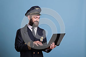 Smiling pilot using laptop, typing message side view