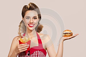 Smiling pin-up girl holding burger and french fries in her hands