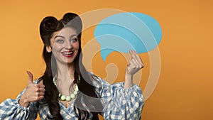 Smiling pin up girl pointing with finger at speech bubble, winking and showing thumb up